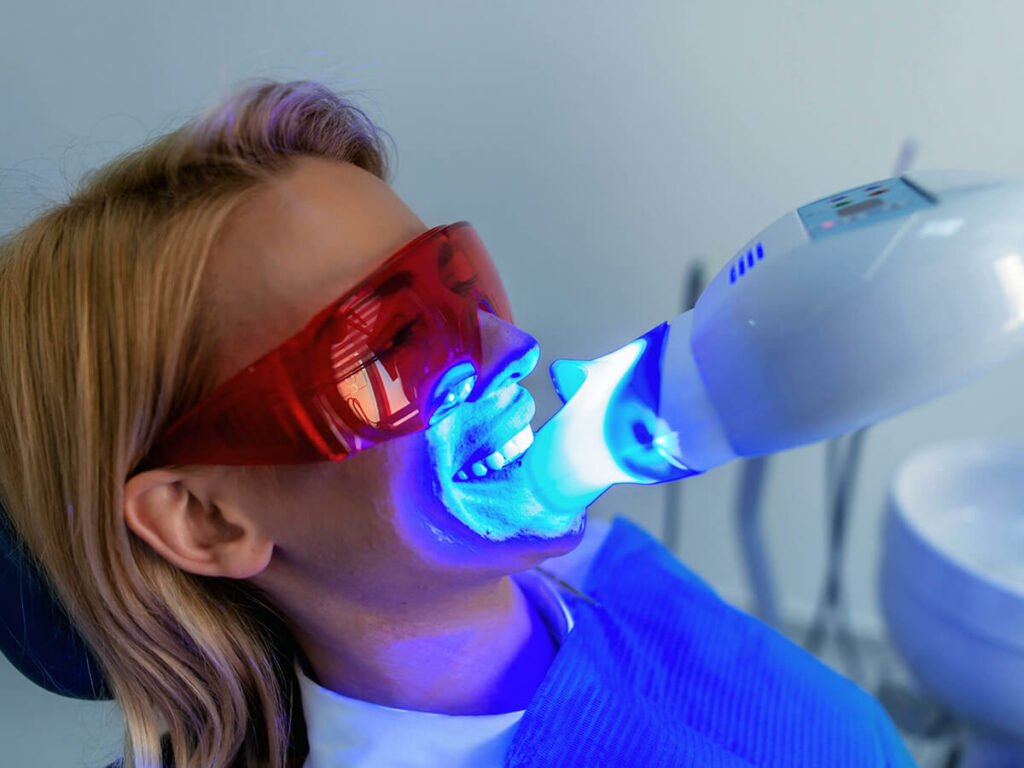 woman at the dentist getting a teeth whitening treatment with blue light